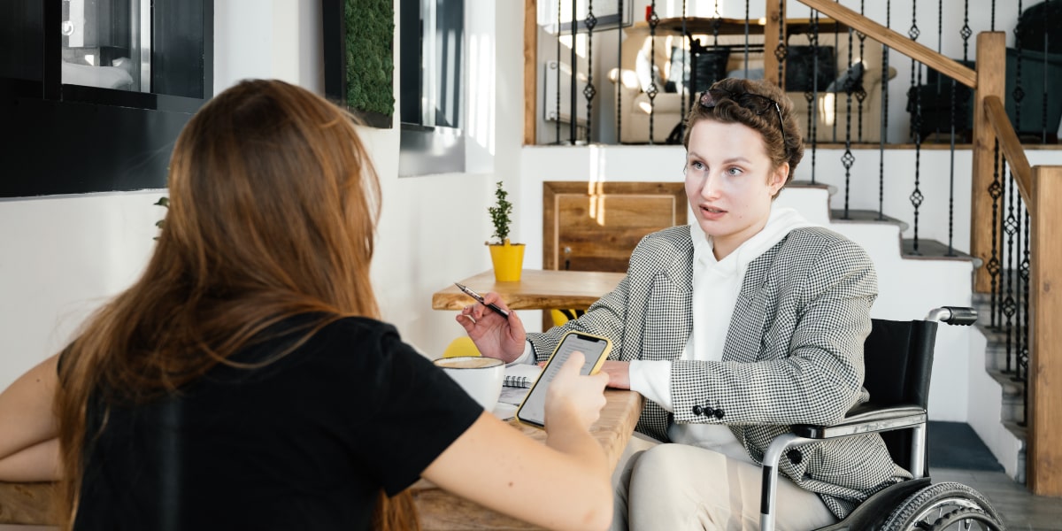 Two UX designers sitting in a coffee shop, sharing ideas.