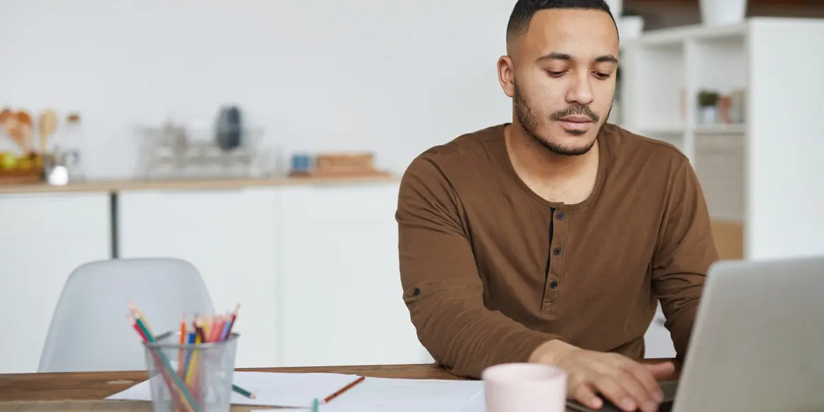 An aspiring UX designer working at a laptop in their kitchen