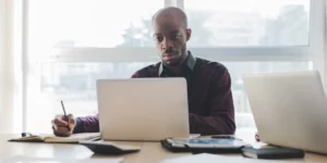 A data analyst sitting at a desk, looking at a laptop