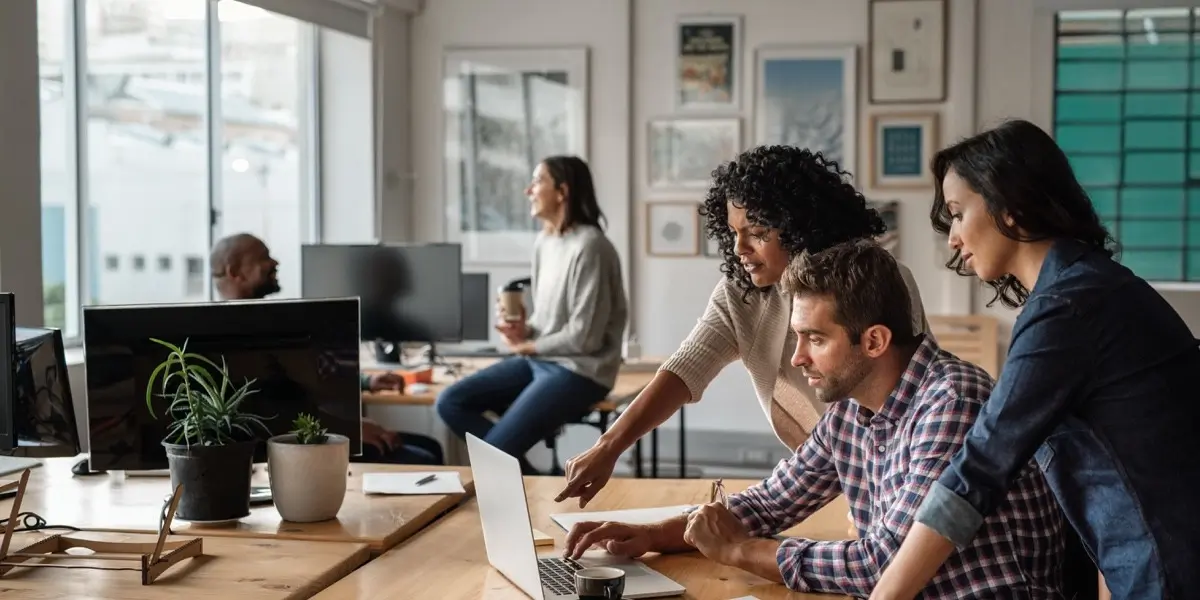 Designers in an office, gathered around a laptop