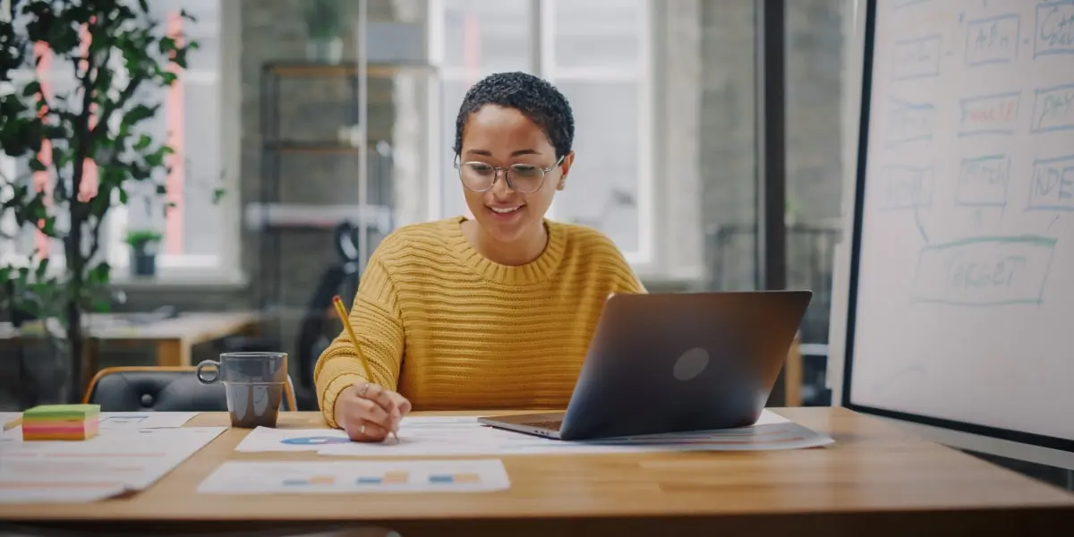 A data analytics student sitting at a desk, writing something down