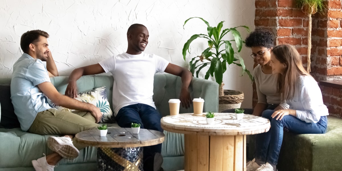 A group of digital marketing bootcamp students sitting in a cafe, chatting and laughing