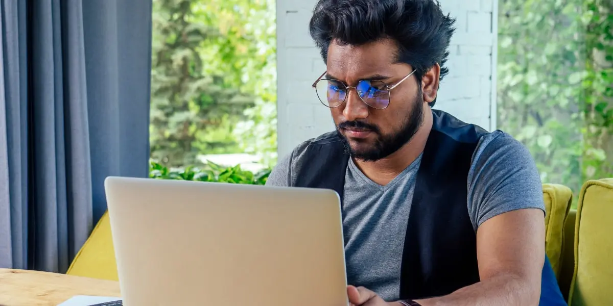 A person working from home, sitting at a desk using a laptop to research the average digital marketing manager salary