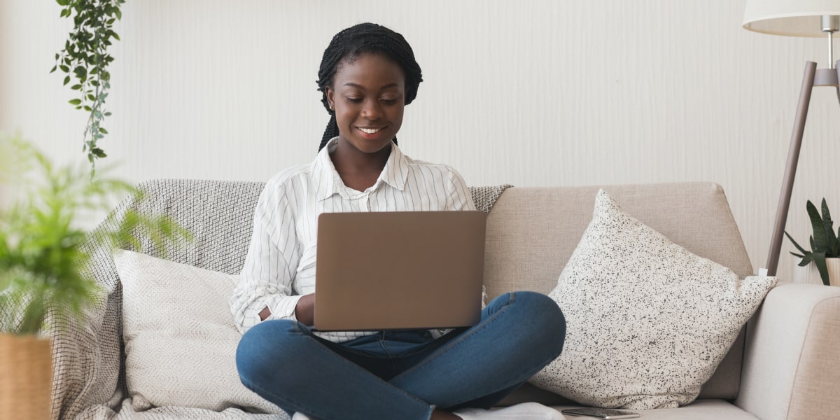 A digital marketing manager sitting on a sofa, looking at a laptop, learning how to track marketing metrics