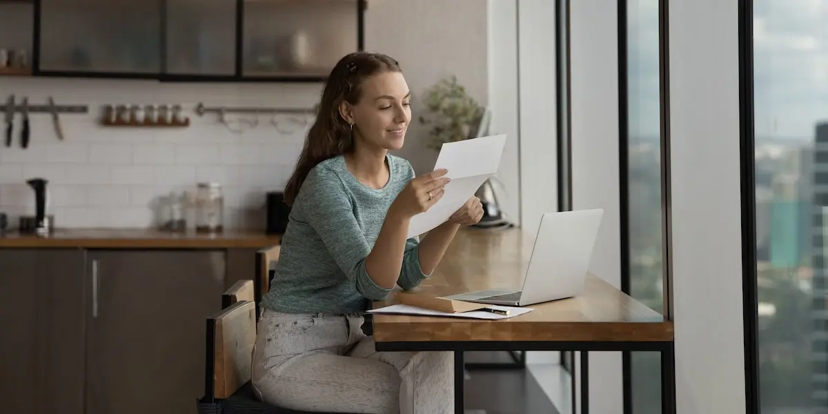 A woman sits with her laptop holding a certificate from her coding bootcamp.