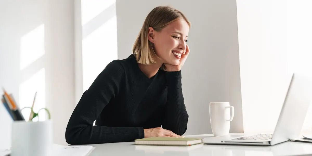 A woman sits at her laptop taking a virtual coding bootcamp at home.