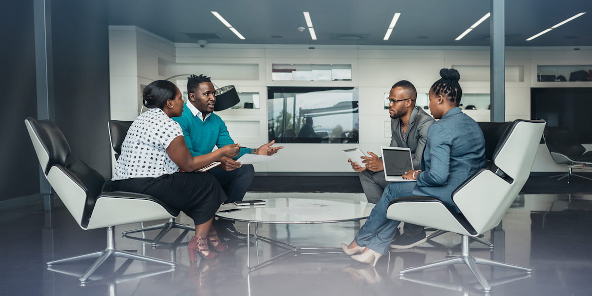 A team of developers sit around a table in a modern office.