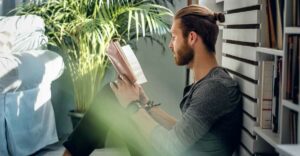 A man sits reading a product management book in his room.