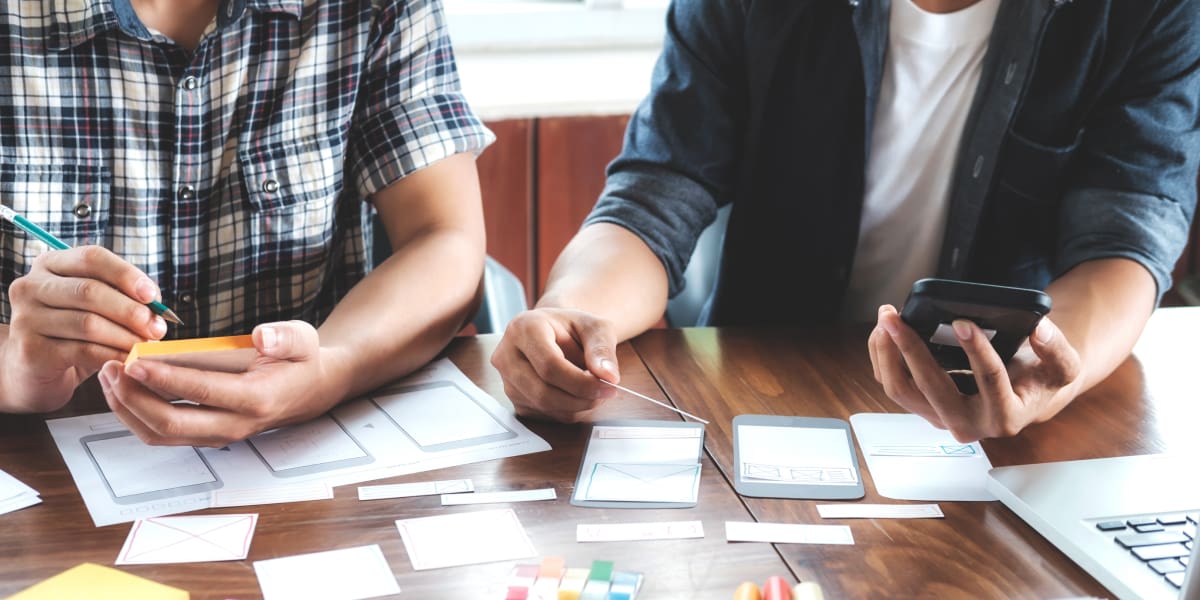 Two UX designers working on paper prototypes for a bootcamp project