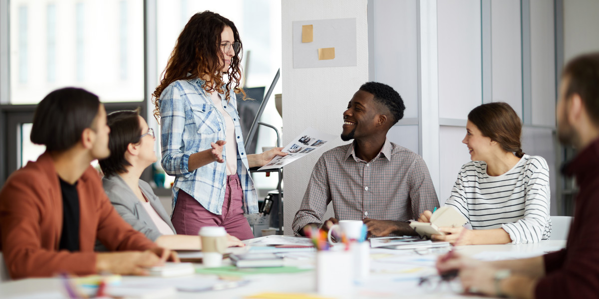 UX designers gathers around a table, smiling and discussing their latest project