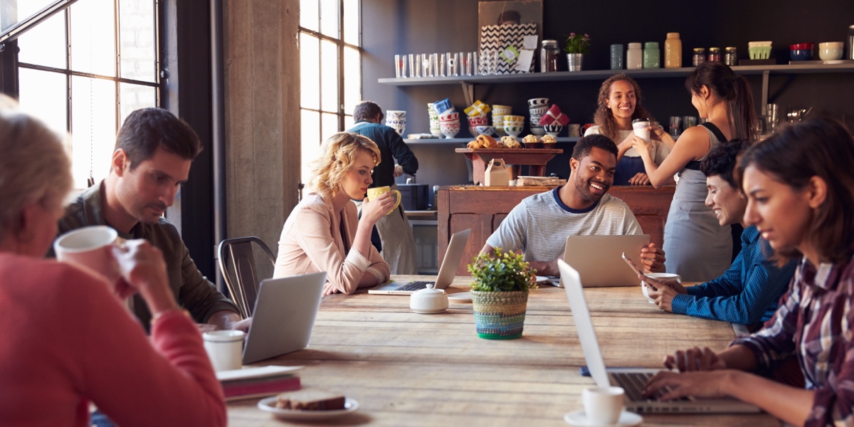 UX Trends 2021: Service Design Interior of a coffee shop, with customers sitting at a communal table and working on laptops