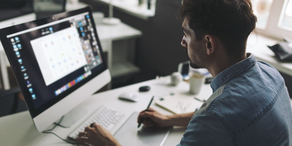 Web developer working on a desktop computer in an office with a stylus pen.