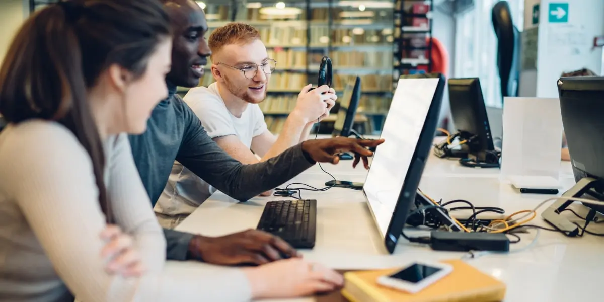 Three web developers looking at some coding framework on a computer screen