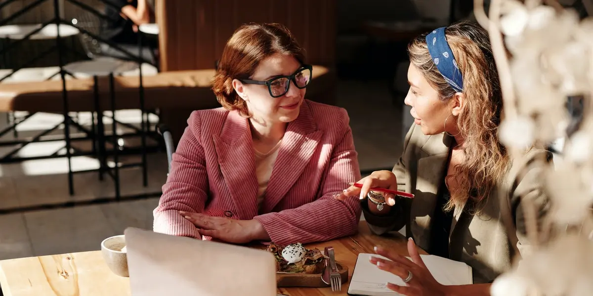 A web developer and UX designer sitting at a café working over a laptop