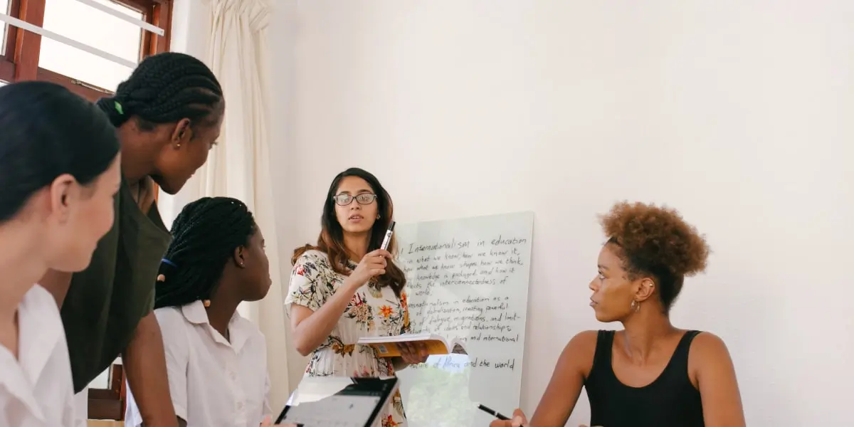 A tech team of women sit in a room and discuss a project.