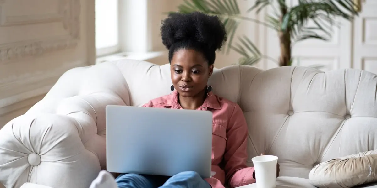 A designer sitting on a sofa, working on a laptop