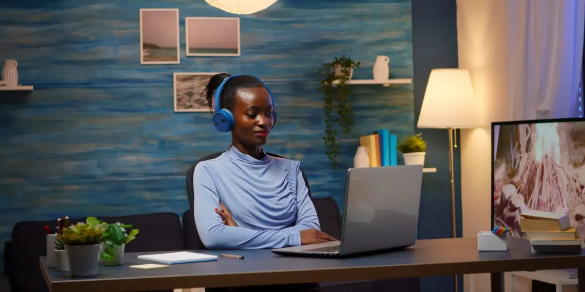 A UI designer sitting at a desk wearing headphones, looking at a laptop