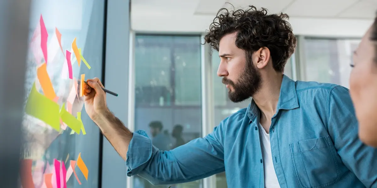 A UX designer in side profile, placing sticky notes on a window