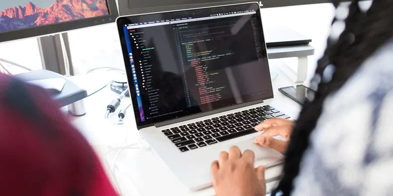 A web developer coding in ES6, a standard of the popular programming language JavaScript, on a laptop.