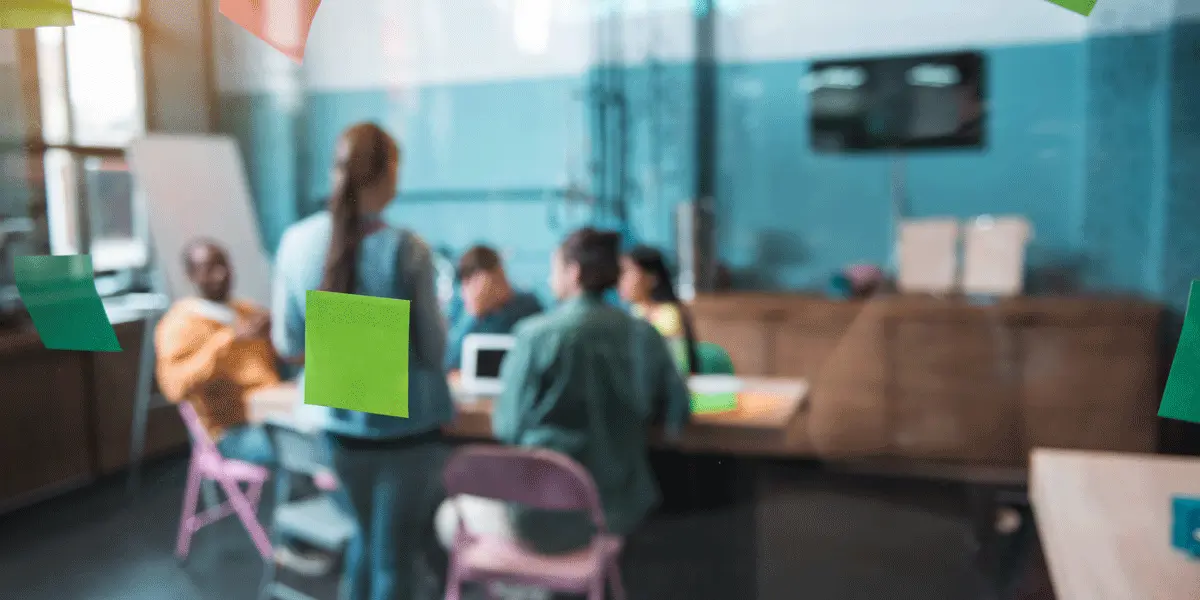 A group of UX designers working at a table behind a glass was covered in sticky notes