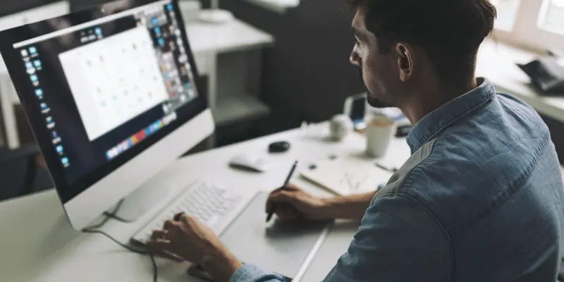 A designer working at their computer, looking at designs and code