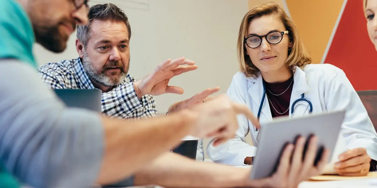 A healthcare data analyst showing colleagues something on an iPad