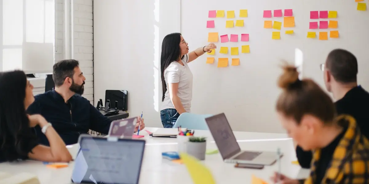 A group of product designers meeting to create an affinity map on a whiteboard with sticky notes