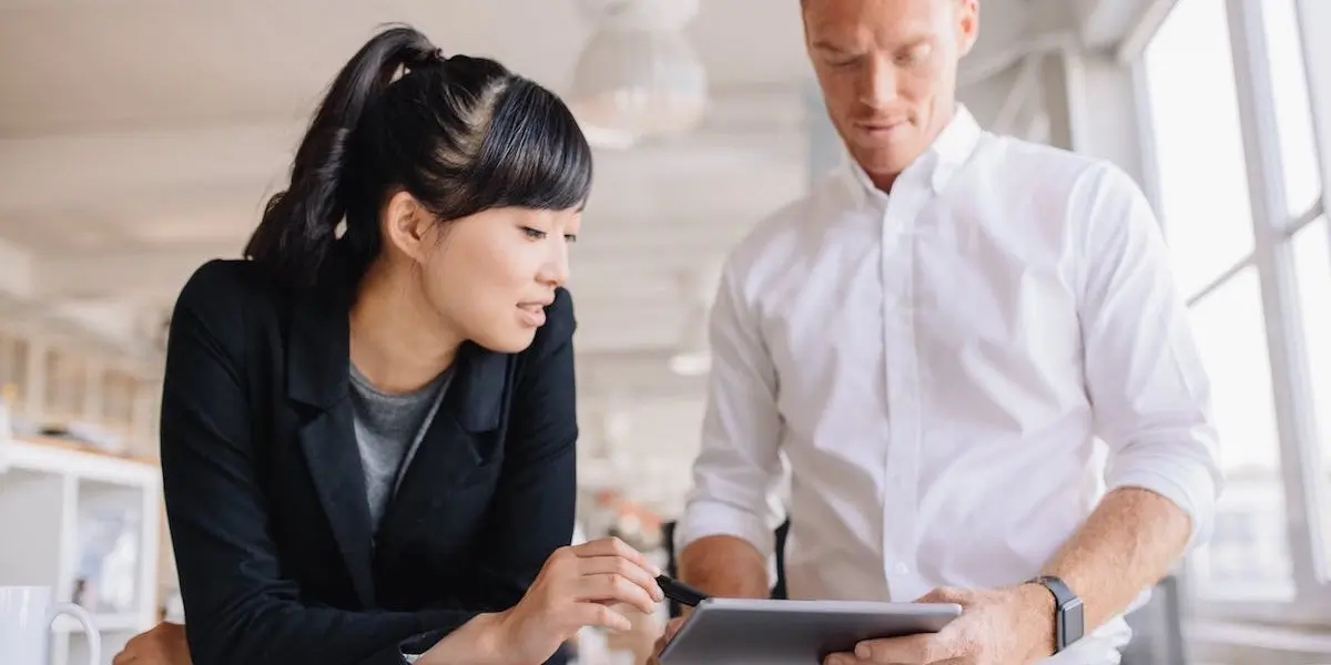 Two UI designers leaning over a desk, looking at an iPad