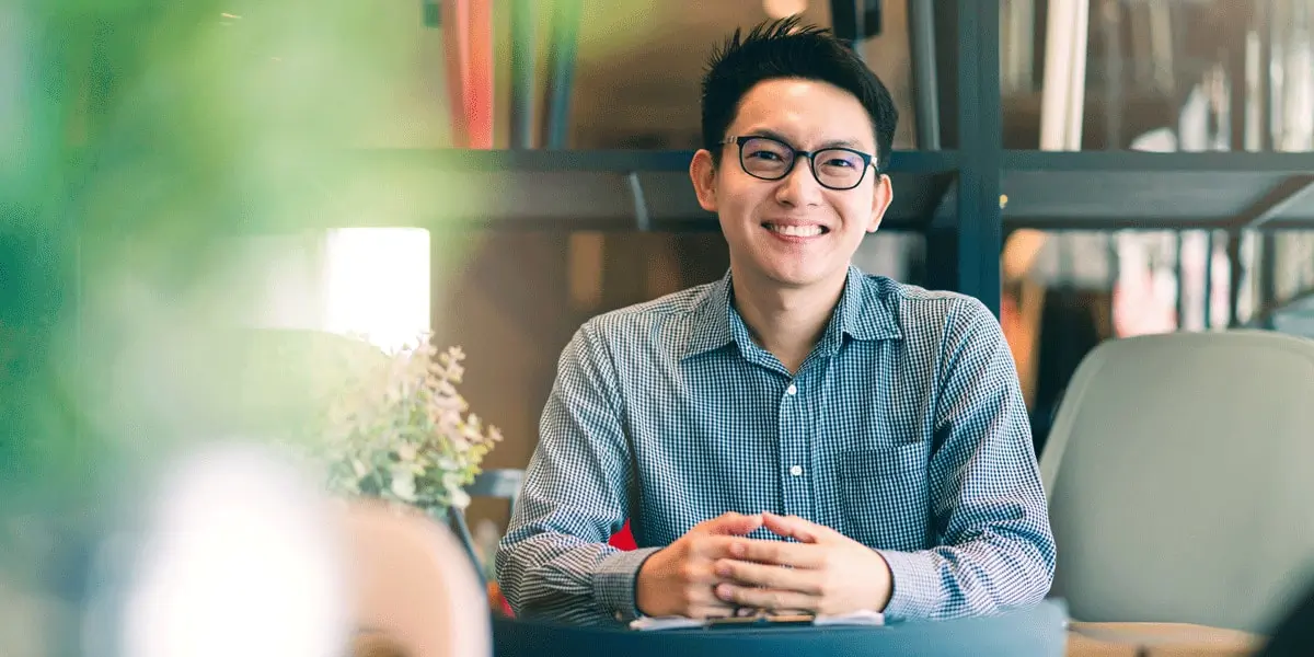 A young smily data analyst sitting in an open plan office