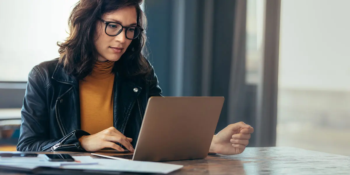 Member of a UX bootcamp at a table with her laptop.