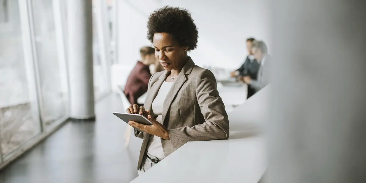 A business analyst leaning on a counter, holding an iPad