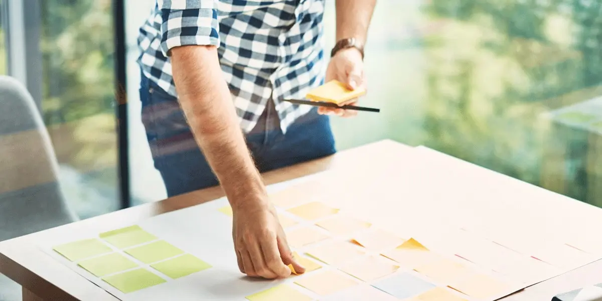 A UX designer standing at a table in a sunny room, doing a card sorting exercise