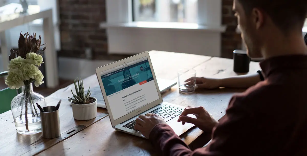 A UX designer sitting at a desk, working on a laptop