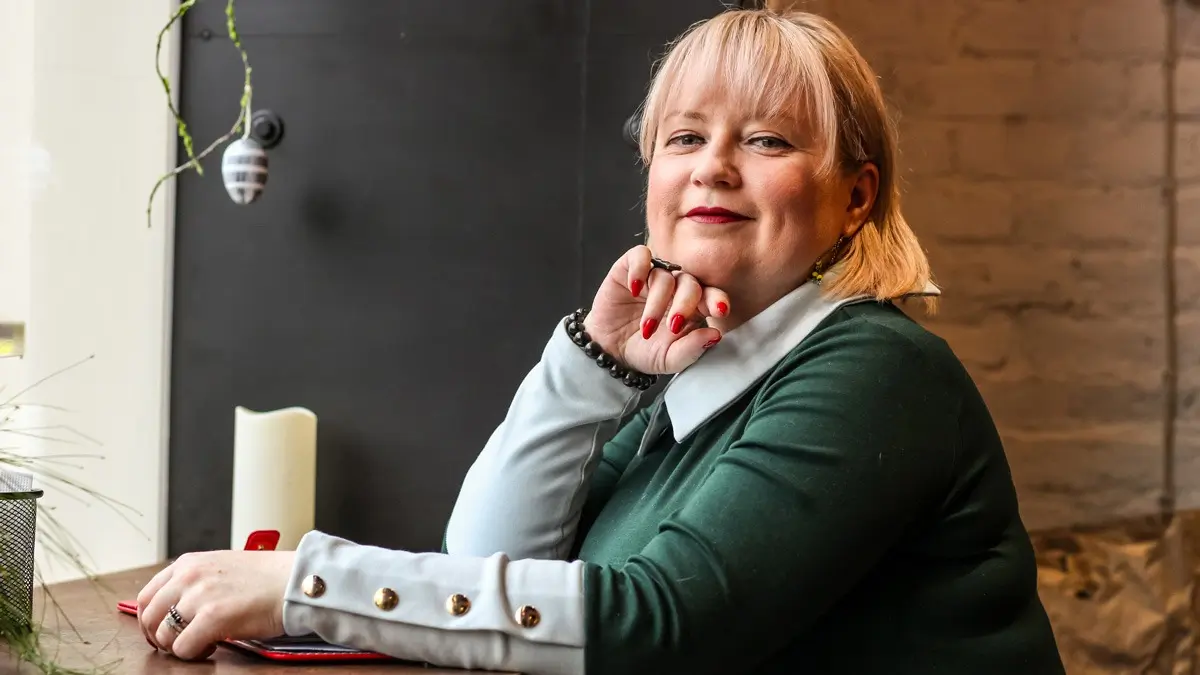 An spiriting UX designer sitting at a desk, smiling at the camera