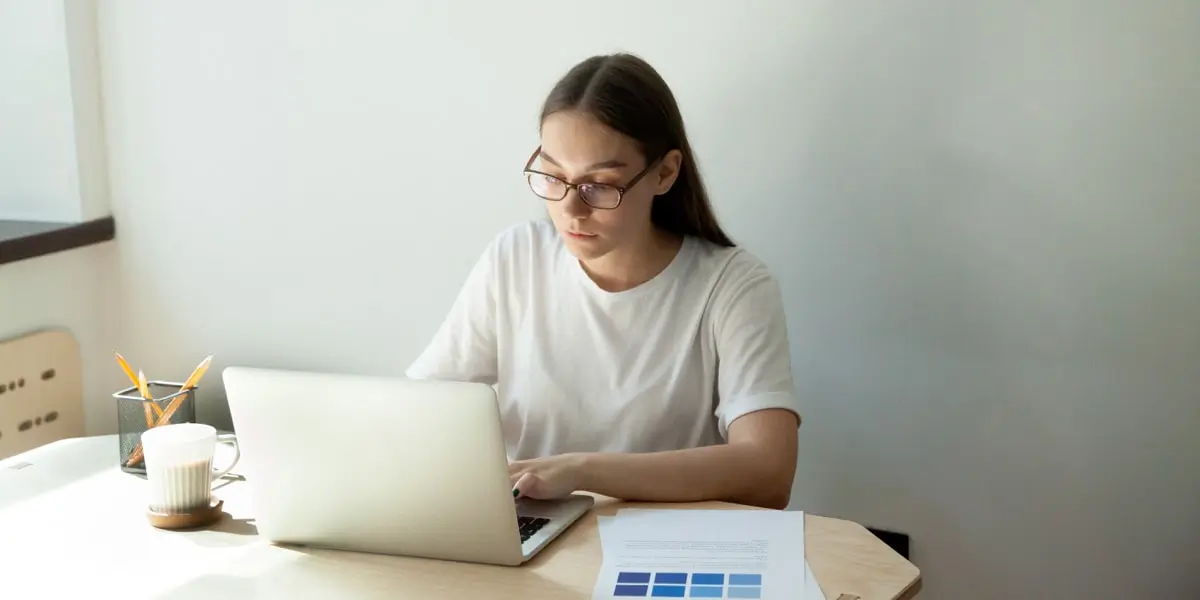 A UI designer sitting at a table, working on a laptop