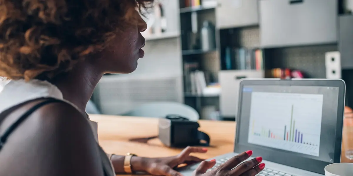 A data analyst in side profile, looking at a laptop screen