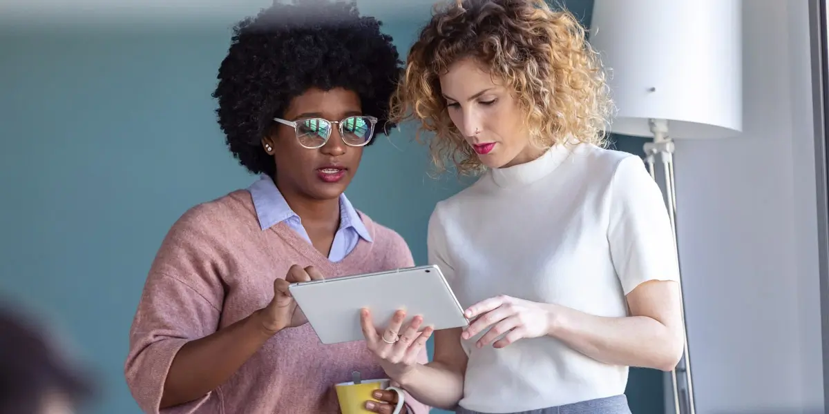 Two data analysts standing side by side, looking at an iPad