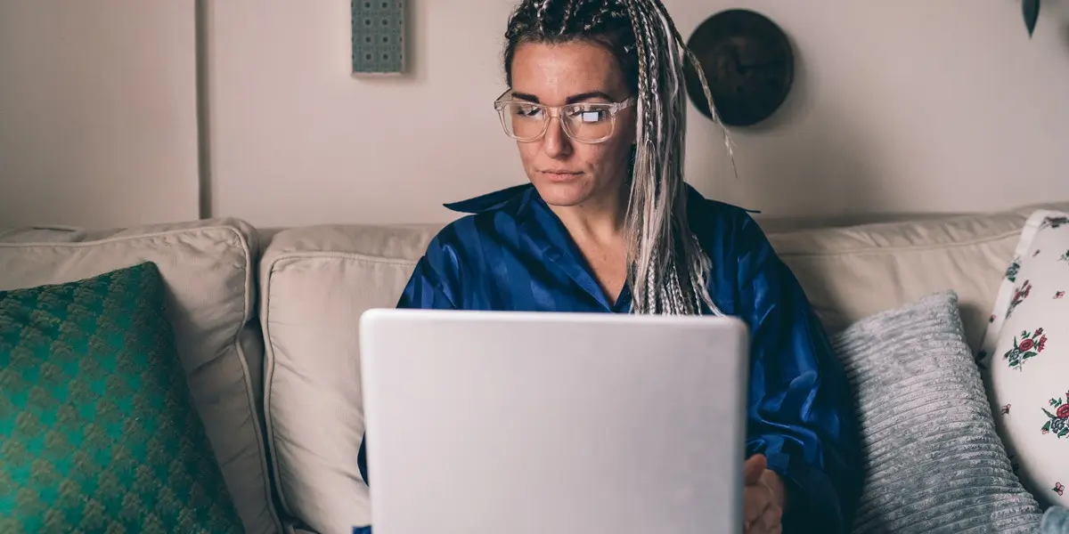 A data analyst sitting on a sofa, looking at a laptop screen