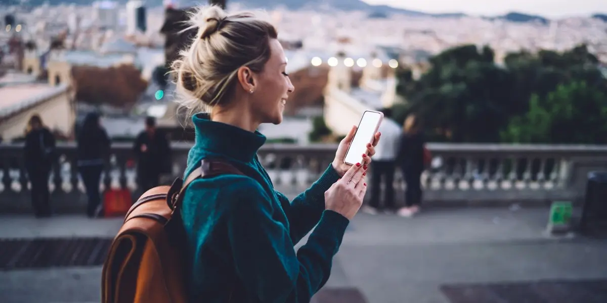 A person in side profile wearing a backpack, holding a mobile phone looking at the best UI design examples