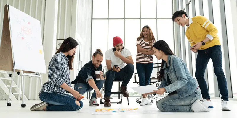 A group of designers gathered around a collection of ideas spread out on the floor