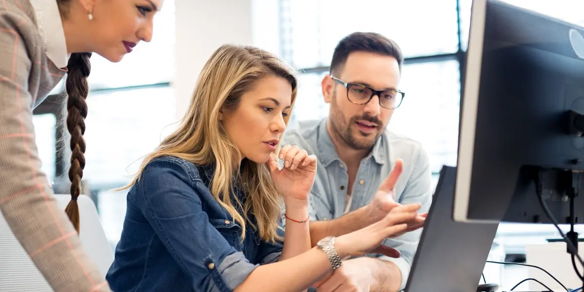 Three data analysts looking at a computer screen