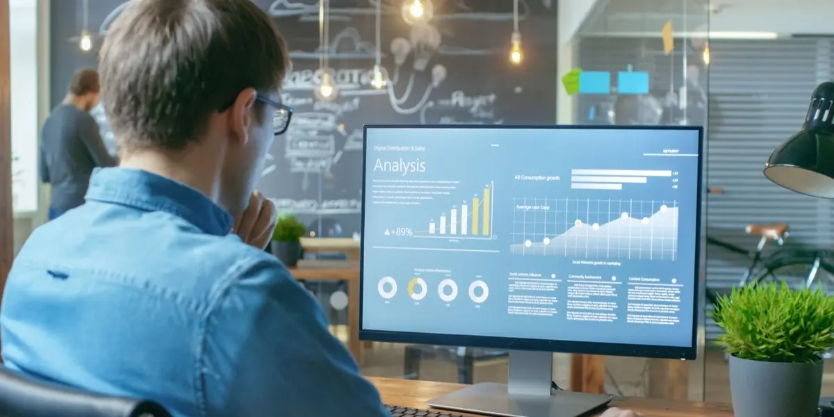 A data analyst looking at graphs on a big computer screen