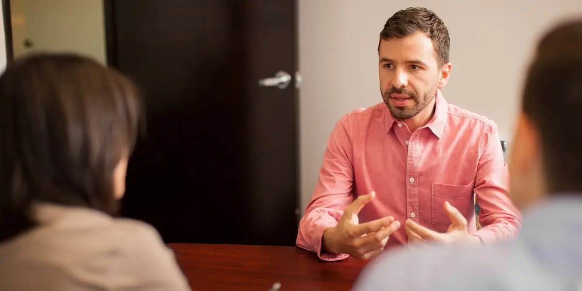 A designer sitting across from two people, conducting user research