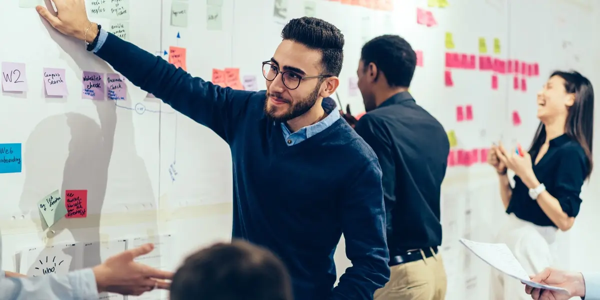 A UX designer standing at a whiteboard, demonstrating a concept