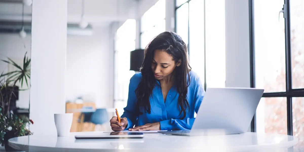 A data analyst sitting at a desk, looking through some notes