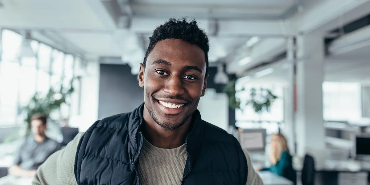 A new UX designer standing in an office, smiling at the camera