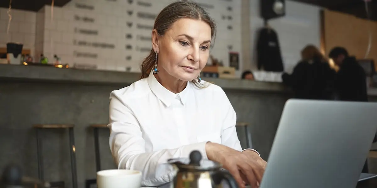 A woman at a laptop in a café learning how to learn coding.