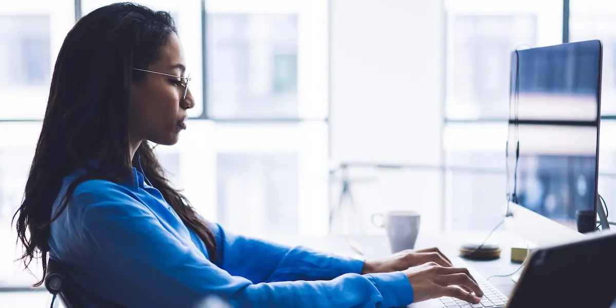 A coder sits at a home office desk using web development tools.