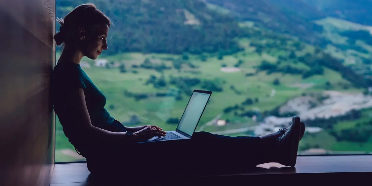 A UI designer in side profile, working on a laptop with a rural backdrop