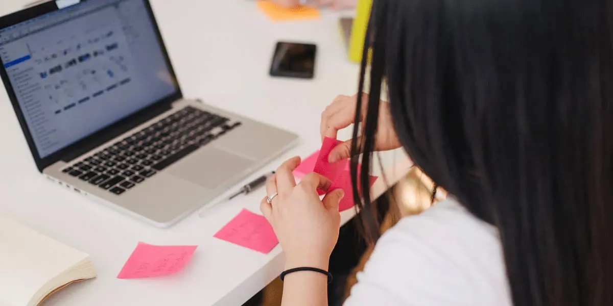 A UI designer writing on a Post-it note